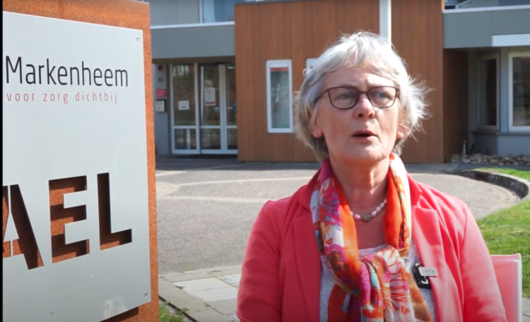 Mevrouw buiten, voor de ingang van een gebouw