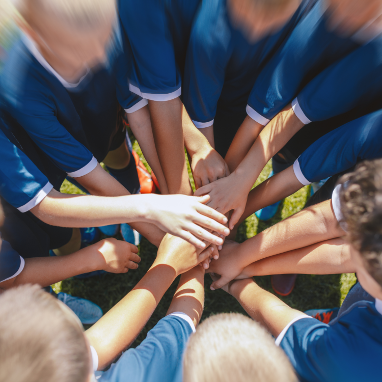 foto van voetballers in een kringetje met de handen op elkaar