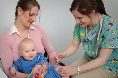 Baby zit bij moeder op schoot en wordt ingeent