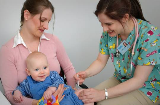 Baby zit bij moeder op schoot en wordt ingeent