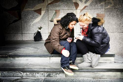 Foto: Twee jongeren met hun telefoon in de hand