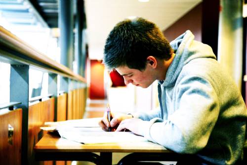 Een tiener maakt huiswerk aan een bureau in de bibliotheek