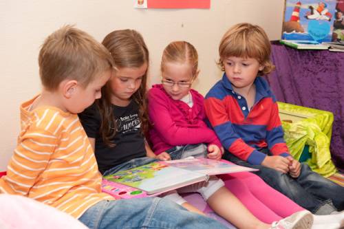 4 kinderen lezen samen een boek