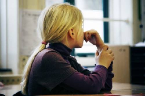 Meisje kijkt voor zich uit. Rond 6 jaar oud. Zit in de klas.