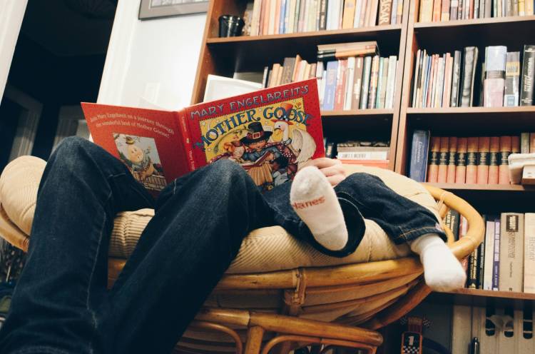 Basisschoolkind leest klein kind voor in een luie stoel