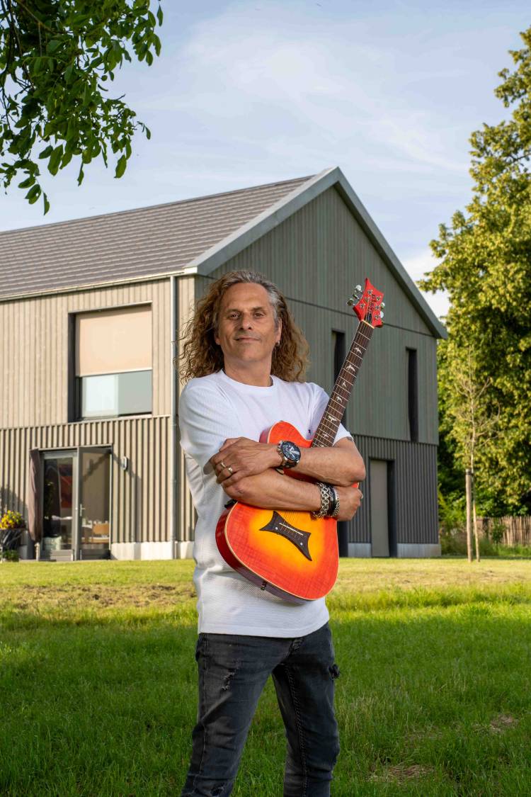Guido Frissen met gitaat in zijn tuin
