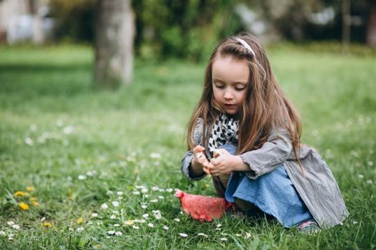 Decoratieve afbeelding: Een meisje plukt bloemetjes in het gras.