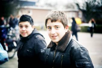 Twee jongens staan op het schoolplein en kijken in de cameralens