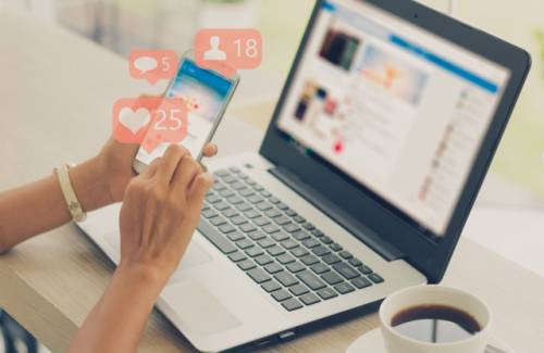 Vrouw zit achter laptop en telefoon