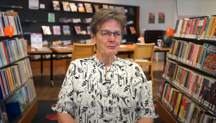 Mevrouw zittend in een bibliotheek