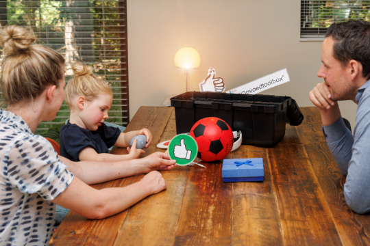 ouders zitten met dochter aan tafel