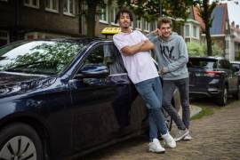 2 jongvolwassenen staan tevreden tegen een taxi aangeleund