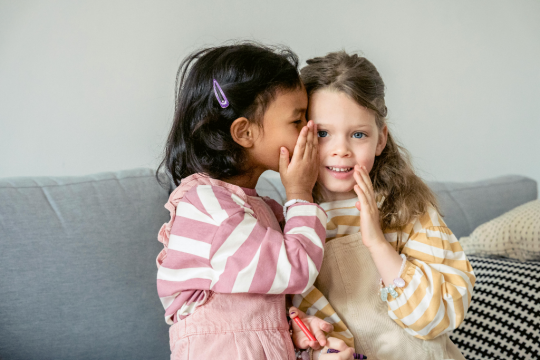 1 meisje fluistert bij ander meisje in haar oor