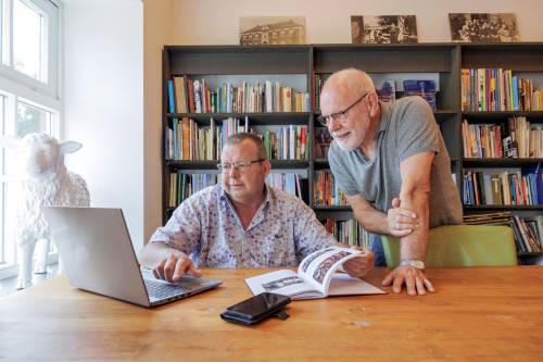 Theo kijkt samen met man naar laptop en boek