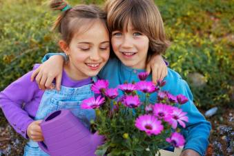 Decoratieve afbeelding: Een foto van twee kinderen met een gieter en een bos bloemen