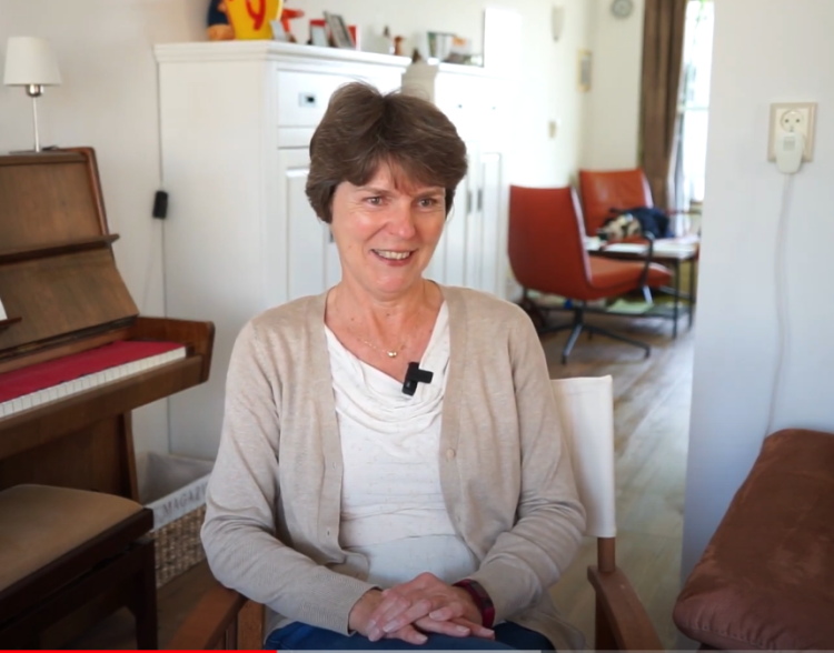 Mevrouw staat achter een stoel in de bibliotheek