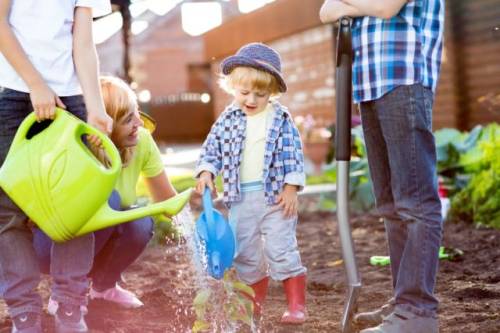 Foto van ouders die met een kind in de moestuin werken