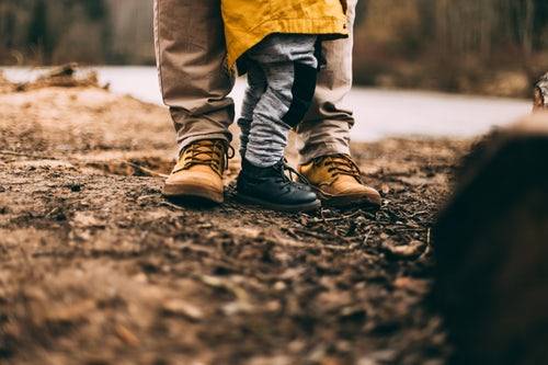 Vader met zoon in bos. Alleen de benen en schoenen zijn zichtbaar.
