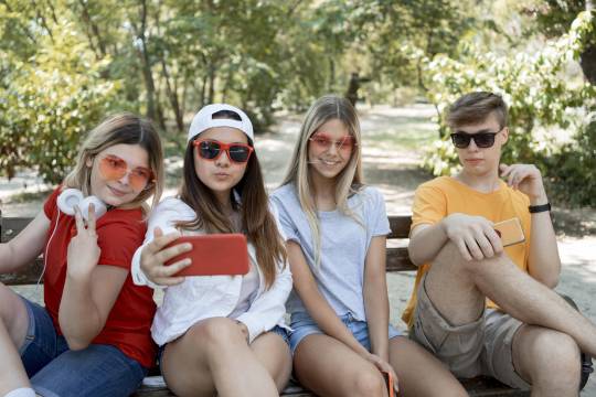 Decoratieve afbeelding: Vier tieners op een bankje. Ze maken een selfie.