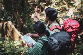 2 jongvolwassenen wandelen in het bos met een rugzak op