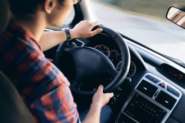 Een jongvolwassene zit achter het stuur van een auto