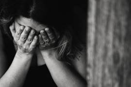 Een vrouw met haar hoofd voorovergebogen en haar handen voor haar gezicht