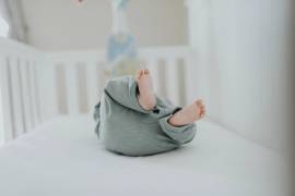 Een baby ligt op zijn rug in een kinderbedje