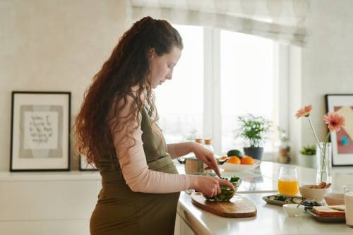 Een zwangere vrouw maakt eten klaar