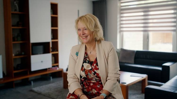 Een lachende vrouw staat in een lokaal.