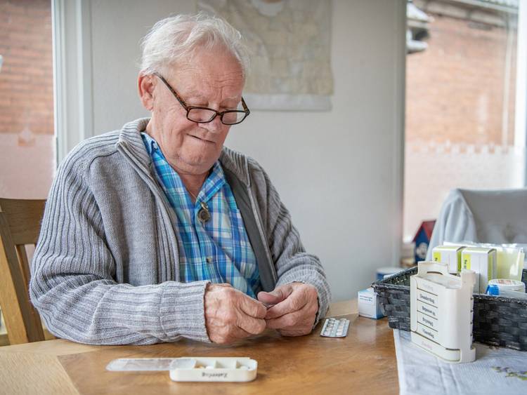Oudere man aan tafel met medicijnen