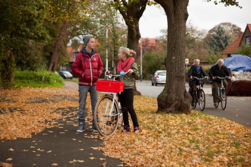2 jongeren op een fietspad met gevallen bladeren op de weg.