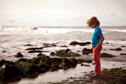 Foto: Jongen staat bij rotsen in de zee