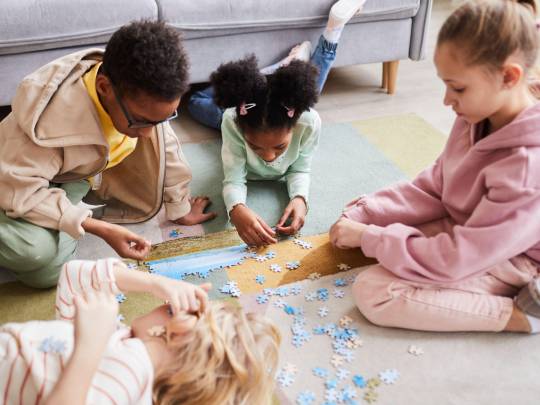 vier kinderen maken samen een puzzel