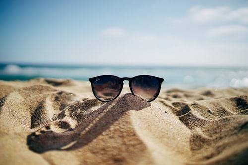 Een zonnebril ligt op het zand van het strand